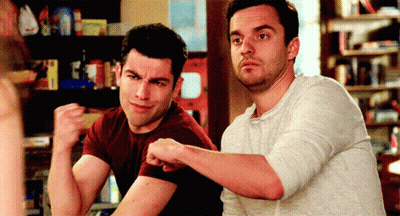 Two Men Are Sitting At A Table And One Of Them Is Flexing His Arms GIF