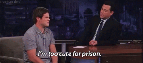 Two Men Are Sitting At A Table And One Of Them Is Saying I 'M Too Cute For Prison GIF