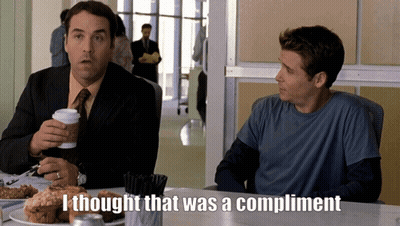 two men are sitting at a table and one of them is saying " i thought that was a compliment "