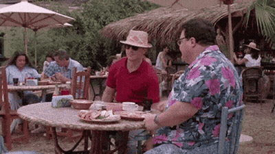 Two Men Are Sitting At A Table Eating Food In A Restaurant . GIF