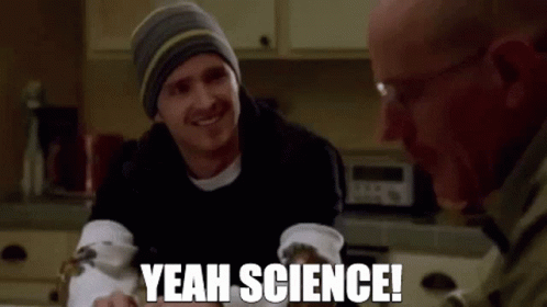 Two Men Are Sitting At A Table In A Kitchen And One Of Them Is Smiling And Saying `` Yeah Science '' . GIF