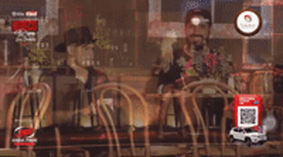 Two Men Are Sitting At A Table In A Restaurant Talking To Each Other GIF
