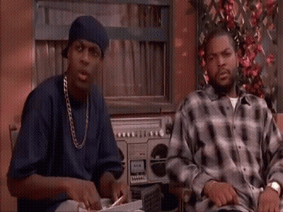 Two Men Are Sitting At A Table In Front Of A Boombox . GIF