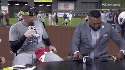 Two Men Are Sitting At A Table In Front Of A Microphone . GIF
