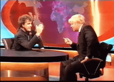 Two Men Are Sitting At A Table Talking In Front Of A World Map GIF