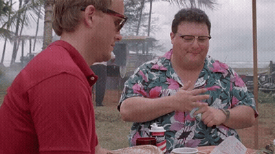Two Men Are Sitting At A Table Talking To Each Other . One Of The Men Is Wearing Sunglasses . GIF