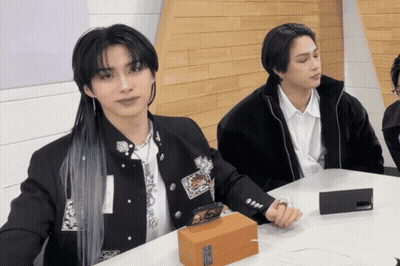 Two Men Are Sitting At A Table With A Box That Says ' Samsung ' On It In Front Of Them GIF