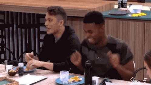 Two Men Are Sitting At A Table With A Plate Of Food And A Bottle Of Water GIF