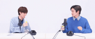 Two Men Are Sitting At A Table With Microphones And Headphones . GIF