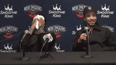 Two Men Are Sitting At A Table With Microphones In Front Of Smoothie King Advertisements GIF