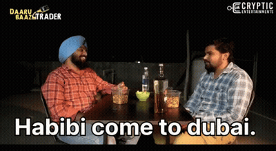 Two Men Are Sitting At A Table With The Words Habibi Come To Dubai On The Screen GIF