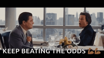 Two Men Are Sitting At A Table With The Words " Keep Beating The Odds " On The Bottom GIF