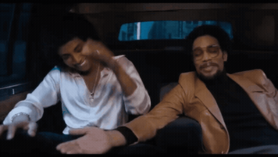 two men are sitting in a car and one is wearing glasses