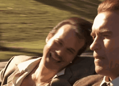 Two Men Are Sitting In A Car And Smiling At Each Other . GIF