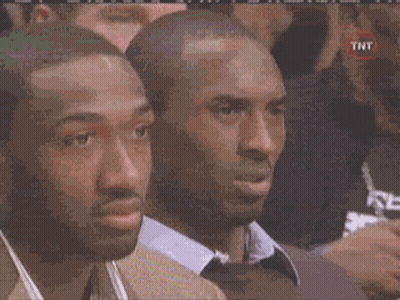 Two Men Are Sitting In A Crowd Watching A Basketball Game And One Of Them Has A Tnt Logo On His Shirt . GIF