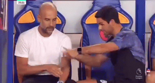 Two Men Are Sitting In A Locker Room Talking To Each Other And One Of Them Is Wearing A Smart Watch . GIF