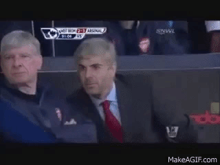 Two Men Are Sitting In A Stadium Watching A Soccer Game And One Of Them Is Wearing A Suit And Tie . GIF