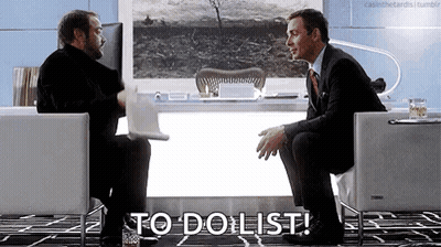 Two Men Are Sitting In Chairs In Front Of A Desk Talking To Each Other And One Of Them Is Holding A Laptop . GIF