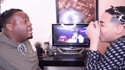 Two Men Are Sitting In Front Of A Computer And One Is Covering His Nose With His Hand GIF