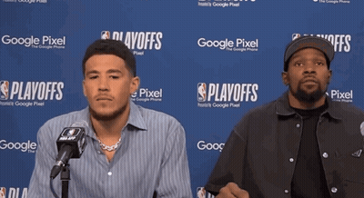 Two Men Are Sitting In Front Of A Google Pixel Sign GIF