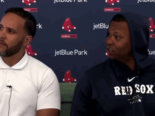 Two Men Are Sitting In Front Of A Jetblue Park Banner GIF