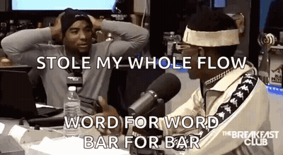 Two Men Are Sitting In Front Of A Microphone And One Of Them Is Holding His Head . GIF