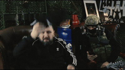 Two Men Are Sitting In Front Of A Microphone With A Sign Behind Them That Says ' Army ' GIF