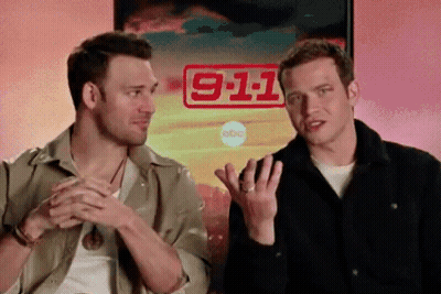 Two Men Are Sitting In Front Of A Poster That Says 911 GIF