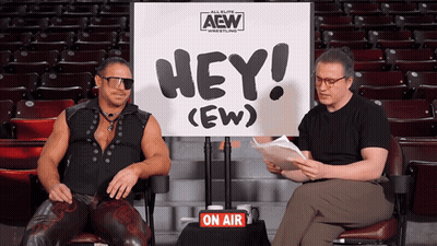 Two Men Are Sitting In Front Of A Sign That Says Hey ( Ew ) GIF