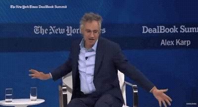 Two Men Are Sitting In Front Of A Sign That Says The New York Times Dealbook Summit GIF