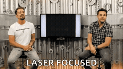 Two Men Are Sitting In Front Of A Tv And The Words Laser Focused Are Visible GIF