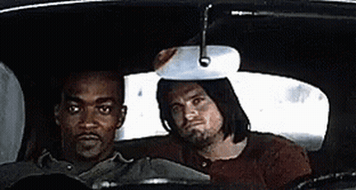 Two Men Are Sitting In The Back Seat Of A Car And Looking At The Rear View Mirror . GIF