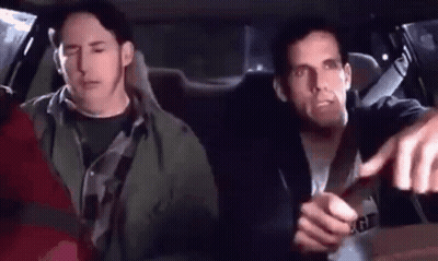 Two Men Are Sitting In The Back Seat Of A Car And One Of Them Is Pointing At The Camera . GIF