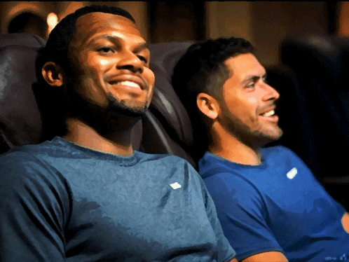 Two Men Are Sitting Next To Each Other In A Chair And Smiling GIF