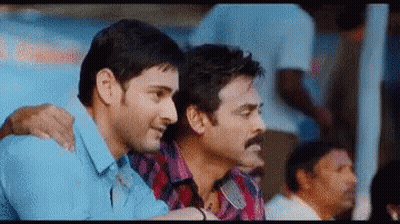 Two Men Are Sitting Next To Each Other In A Crowd Of People . GIF