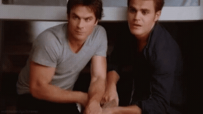 Two Men Are Sitting Next To Each Other In A Room Holding Hands . GIF