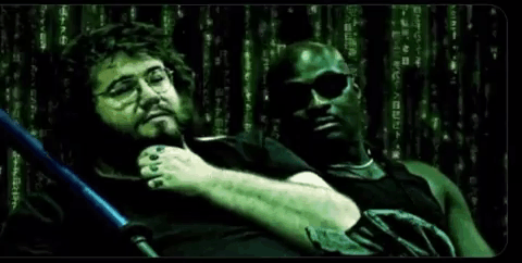 Two Men Are Sitting Next To Each Other In Front Of A Matrix Screen . GIF