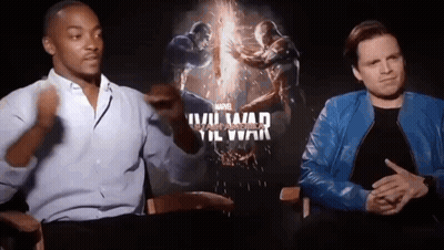 Two Men Are Sitting Next To Each Other In Front Of A Movie Poster For A Movie . GIF