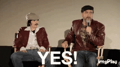 Two Men Are Sitting Next To Each Other On A Couch And One Is Holding A Microphone And The Other Is Saying Yes . GIF