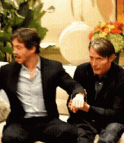 Two Men Are Sitting Next To Each Other On A Couch Holding Hands . GIF
