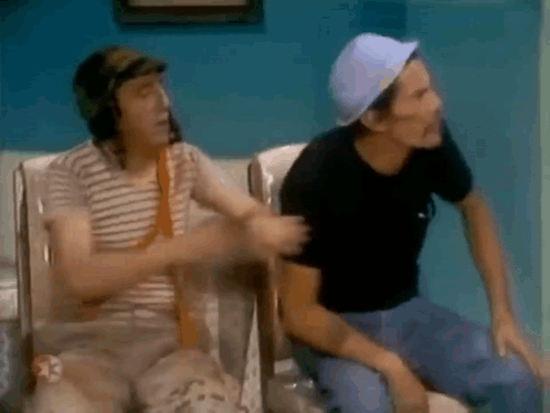 Two Men Are Sitting Next To Each Other On A Couch In A Room . GIF