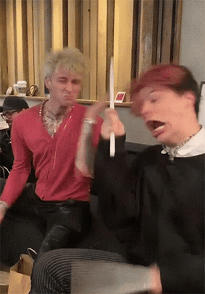 Two Men Are Sitting Next To Each Other On A Couch Playing With A Toy . GIF