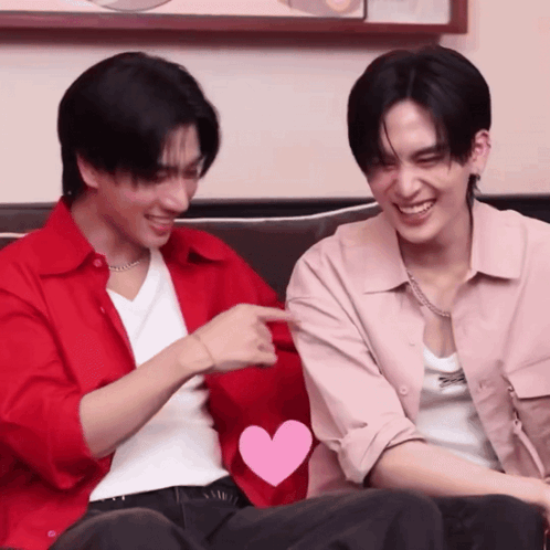 Two Men Are Sitting Next To Each Other With One Pointing At The Other GIF