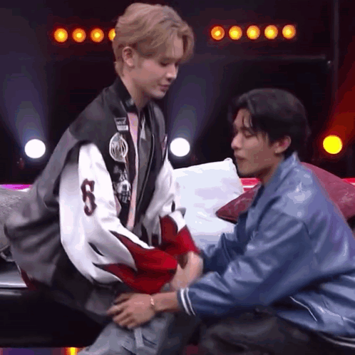 Two Men Are Sitting On A Couch And One Of Them Is Holding The Other 'S Arm . GIF