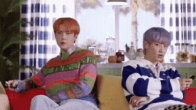 Two Men Are Sitting On A Couch In A Living Room . GIF