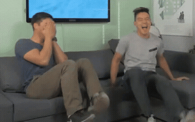 Two Men Are Sitting On A Couch Laughing And Covering Their Eyes GIF