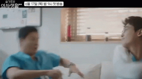 Two Men Are Sitting On A Couch Talking To Each Other In A Living Room . GIF