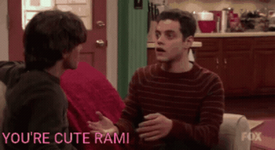 Two Men Are Sitting On A Couch With The Words You 'Re Cute Rami Written On The Bottom GIF