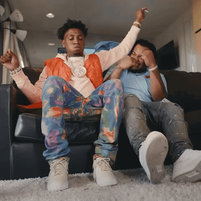 Two Men Are Sitting On A Couch With Their Arms Up GIF