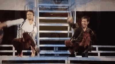 Two Men Are Sitting On A Stage With Their Arms Outstretched And A Dog In The Background . GIF